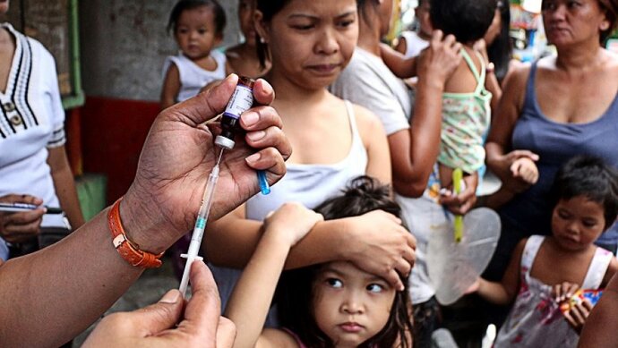 A city health worker prepares to vaccinate a young girl against polio and measles during free home vaccination in Mandaluyong City, Philippines. Credit - 2014 Gregorio, Jr. Dantes, courtesy of Photoshare