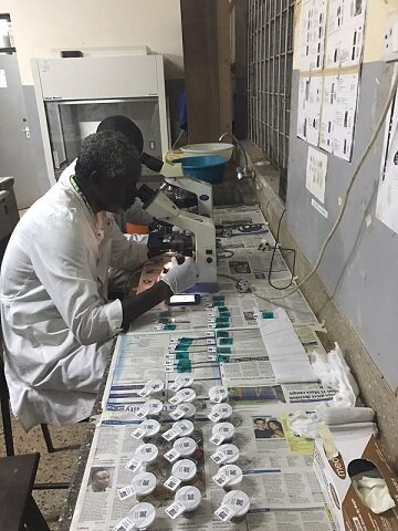 TUMIKIA lab technician preparing sample slides to measure STH prevalence. Image courtesy of LASER